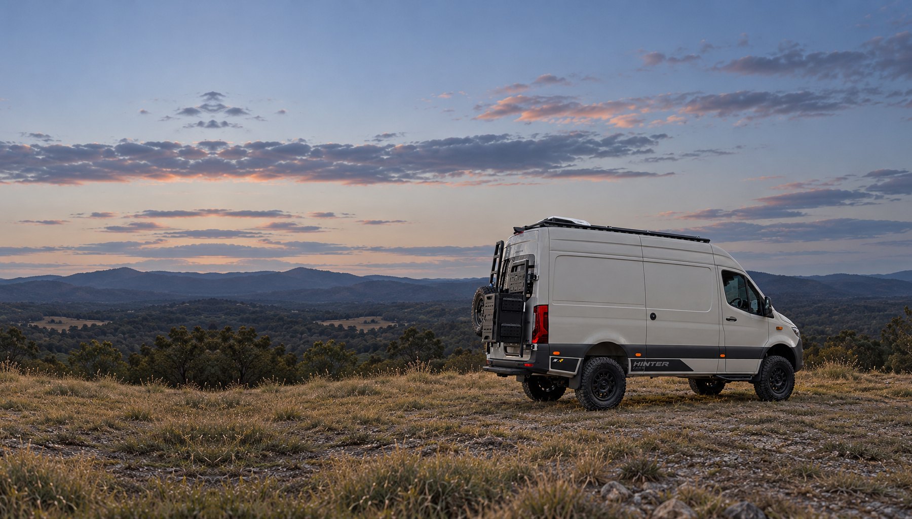 A Hinter Vans Sprinter parked on a hilltop overlooking the ranges at dusk